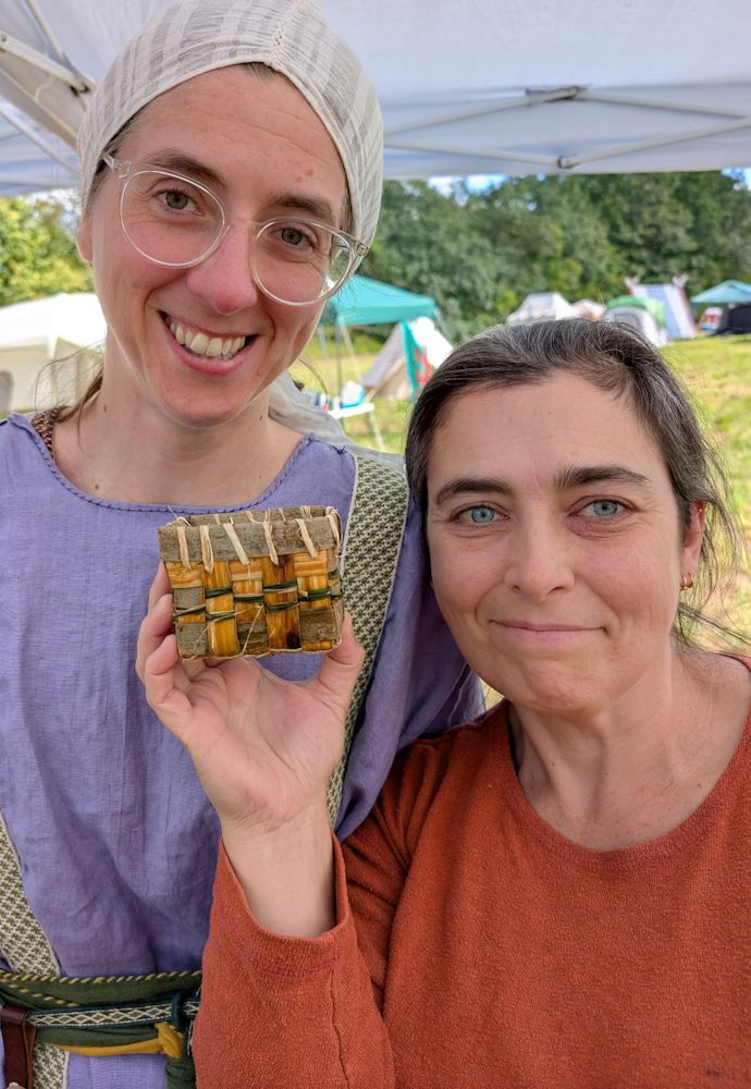 One student with their basket and  the author: the basket sides are vertical bark strips secured with horizontal bands of grass, and the top band is secured with a thin strip of inner willow bark used like thread to whip stitch the top.