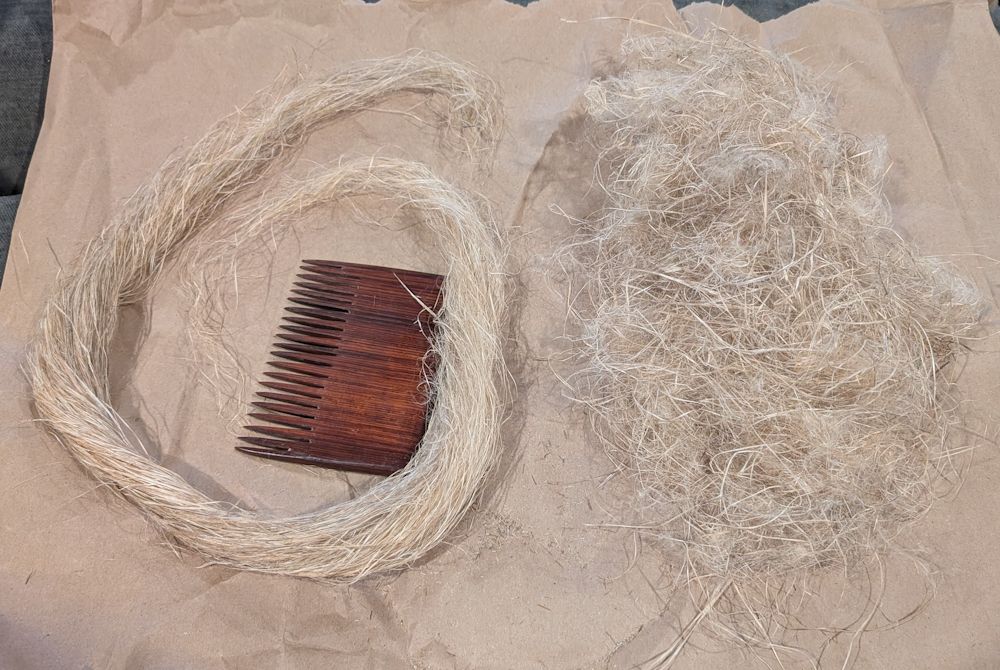A fully combed white hank of straight, organized, long fibers is curled into a loop on the left, while a disorganized and chaotic pile of white fibers sits on the right.