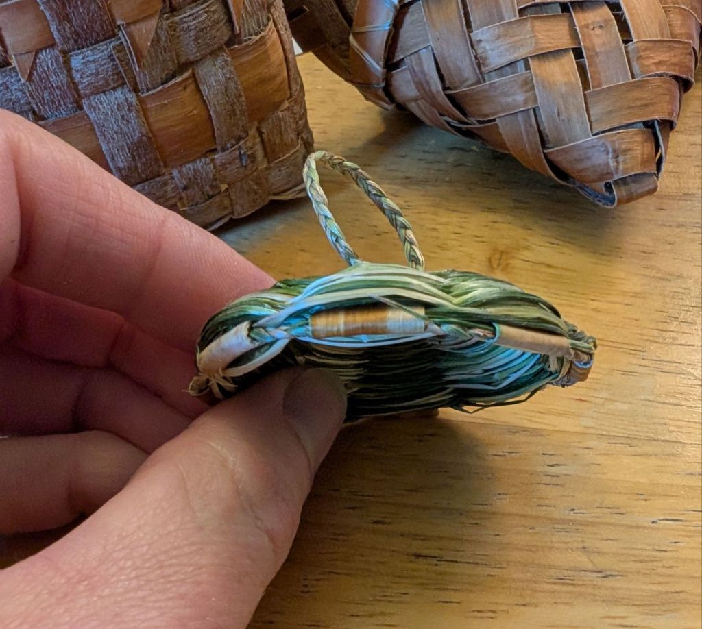 Edge view of the unfinished lid, showing the spokes after they were folded over and tucked in.